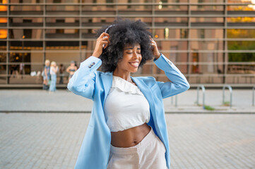 Stylish businesswoman enjoying music with headphones in urban city