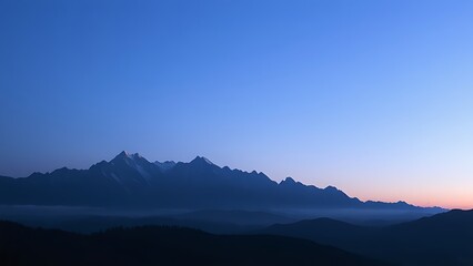 Majestic mountain range during blue hour, with a soft gradient of twilight colors.