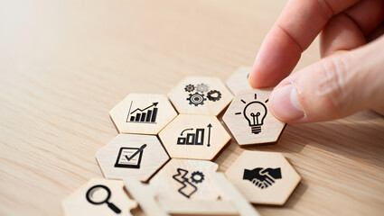 Hand placing a hexagonal tile with a lightbulb icon onto a cluster of business strategy icons