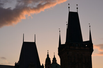 This is a silhouette shot of Prague's old town towers against a sunset sky. The photo highlights the distinct, jagged spires and rooftops of the city
