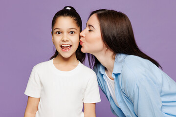 Close up young woman wear blue casual clothes have fun with child baby girl 8-9 years old. Mommy little kid daughter hug cuddle kiss on cheek isolated on plain purple background. Mother's Day concept