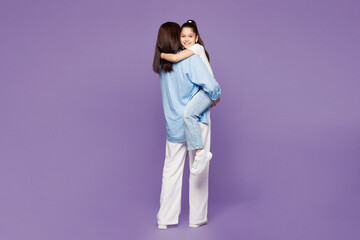 Full body back view young woman wear blue casual clothes have fun with child baby girl 8-9 years old. Mommy hold little kid daughter in hands isolated on plain purple background. Mother's Day concept. © ViDi Studio
