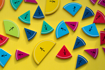 Colorful fraction learning tools arranged on a yellow background for educational purposes