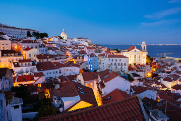 Panoramic Night View Over Alfama’s Rooftops and Tagus River from Miradouro da Graca Viewpoint in Lisbon, Portugal