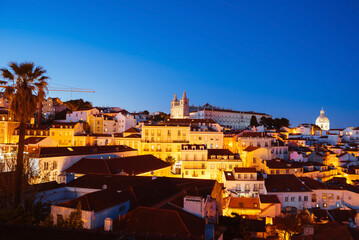 Panoramic Night View Over Alfama’s Rooftops and Tagus River from Miradouro da Graca Viewpoint in Lisbon, Portugal