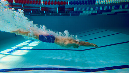 Professional swimmer underwater glide with bubbles after dive. Concept of athletic focus, speed,...