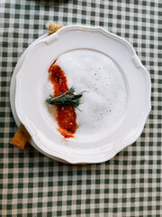 Unique culinary presentation with foam and spices on a white plate