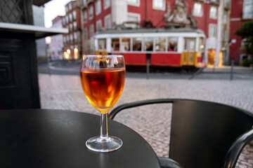 Glass of Port Wine on Lisbon Cafe Table with Famous Yellow Tram in Background. Lisbon, Portugal
