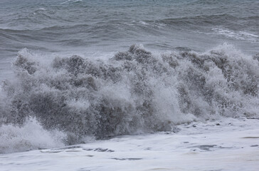 A large wave is crashing on the shore