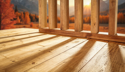 Empty wooden patio surface outdoors with warm autumn sunlight rays shining across the scene with copy space for product placement. The blurred autumn background and cozy seasonal mood. 