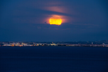 Full Moon, supermoon, blood moon Rising Above the Illuminated Night Skyline of Historic Lisbon, Portugal
