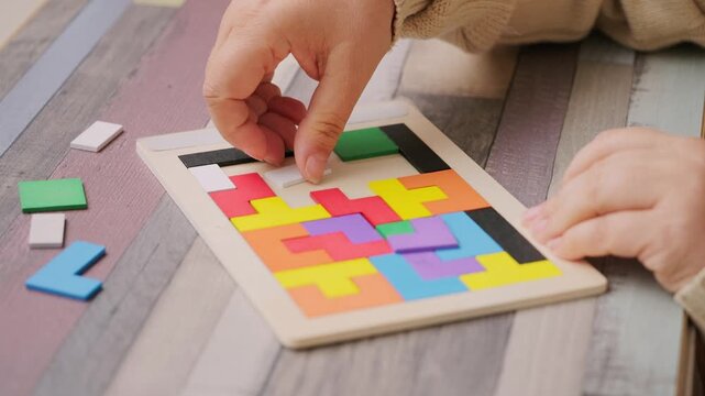 hands carefully placing colorful wooden geometric shapes intellectual puzzle, therapy cognitive training, dementia aid, brain health, occupational therapy, logical thinking, mental exercise