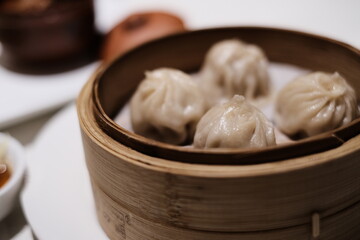 Chopsticks lifting a xiao long bao (steamed dumpling) served hot on a steaming tray xiaolongbao 小籠包