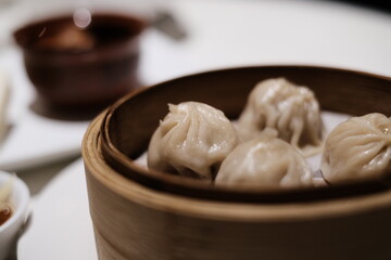 Chopsticks lifting a xiao long bao (steamed dumpling) served hot on a steaming tray xiaolongbao 小籠包