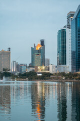 evening panorama of Bangkok city skyline with skyscrapers and Benchakitti park lake, vibrant cityscape view with reflections over pond water at dusk