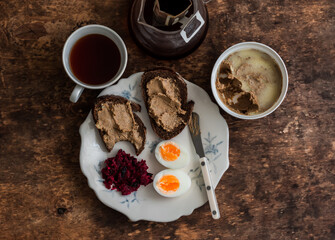Delicious breakfast, snack - toasts with pate, boiled egg, beetroot salad and coffee on a wooden table, top view