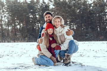Obraz premium Happy family enjoying snowy weather in the forest and having fun together