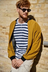Obraz premium Charming young redhead man showcasing autumn fashion in an urban setting