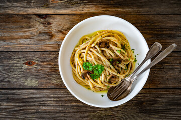 Pasta with champignons mushrooms in creamy sauce and parsley on wooden table	