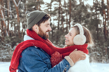 Man and woman looking romantic while having a walk in a winter forest