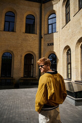 Naklejka premium Stylish young redhead enjoying autumn in an urban courtyard setting