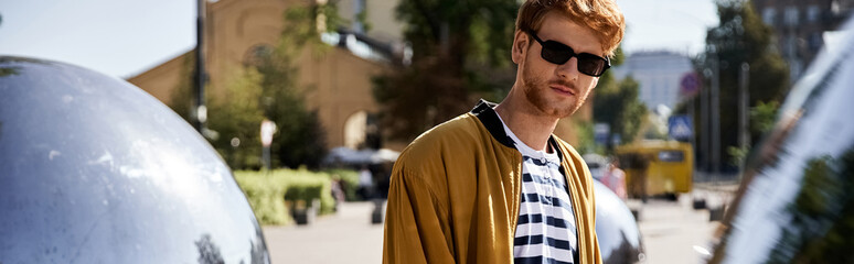 Stylish redhead man enjoying a sunny day in the urban autumn landscape