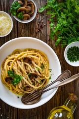 Pasta with champignons mushrooms in creamy sauce and parsley on wooden table	