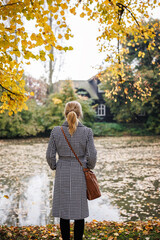 Thoughtful woman standing in autumn park, expressing melancholy and pensive mood of solitude