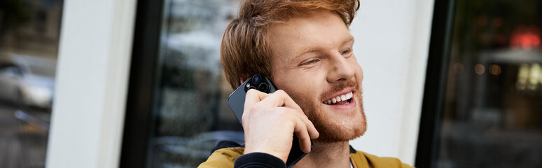 Redhead man in a stylish autumn outfit enjoys an urban day on the phone