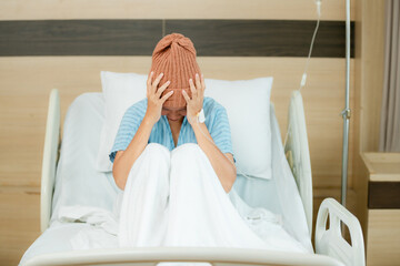 Asian young woman in bed suffering from cancer. Young patient headscarf recovery in hospital on bed.
