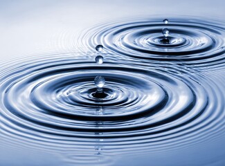 Water droplets impacting a still surface, creating concentric ripples