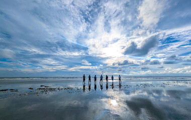Friends on the Beach Beneath a Dramatic Reflective Sky