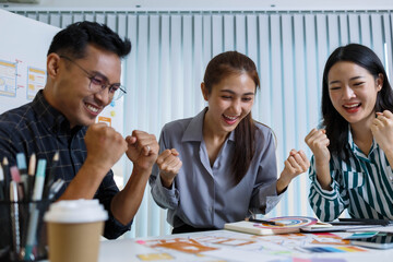 A man and two women are sitting at a table with a white background. The man is drawing on a white board while the women look on. Scene is collaborative and creative
