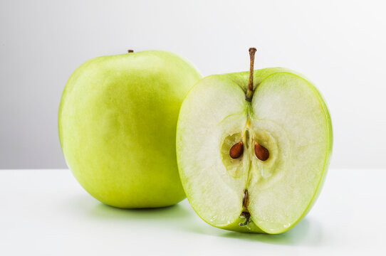 Still life of apples, one halved.
