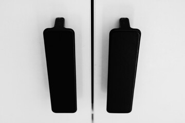 Sleek and minimalist black cabinet handles mounted on a pristine white furniture surface, showcasing contemporary interior design aesthetics and modern simplicity in home decor