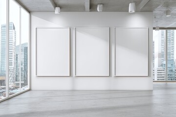 Three blank white framed canvases on a light-gray wall of a modern, bright interior with large windows showcasing a city view