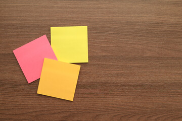 Colored Sticky Notes on Wooden Desk. Bright colored sticky notes arranged on wooden table background, ideal for reminders, messages, and creative mockups.