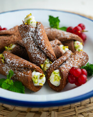 Sicilian cannoli filled with ricotta cheese cream and topped with chopped pistachios.