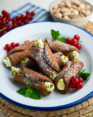 Sicilian cannoli filled with ricotta cheese cream and topped with chopped pistachios.