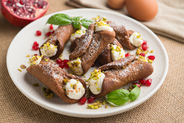 Sicilian cannoli filled with ricotta cheese cream and topped with chopped pistachios.