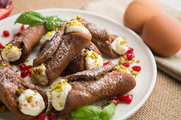 Sicilian cannoli filled with ricotta cheese cream and topped with chopped pistachios.