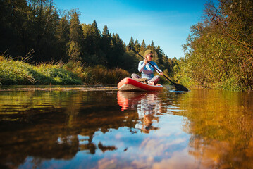 A girl is surfing on a sup board on small river at sunny day.