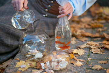 women's hands hold a container of water in which fish are swimming