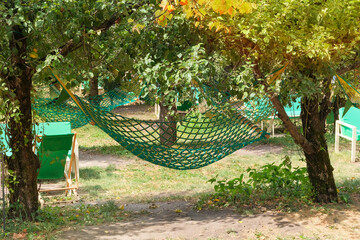 Hammock in a summer apple orchard. Cottage garden. Carefree rest and relax. Weekend.