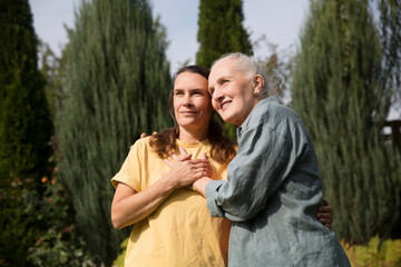 an elderly woman hugs her adult daughter near the house in the garden. Deep conversation. emotional intimacy. support in two age generations