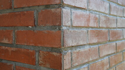 Red clay brick masonry wall detail at a building corner, showing stretcher bond pattern and mortar...
