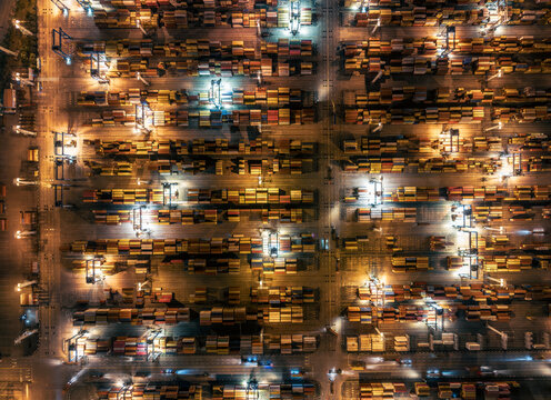 Busy container terminal with colorful cargo boxes illuminated at night.