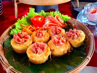 This traditional Indonesian cake is called Tahu Fantasi, made from tofu and filled with meat and vegetables. It is served on a bamboo woven “tempeh” tray, which is both artistic and delicious.