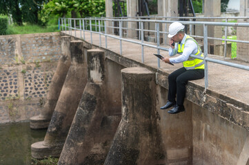Dam official is checking the water level in the dam and recording it on paper