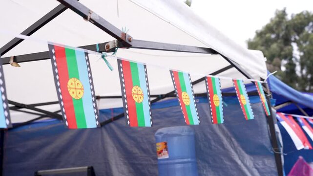 Small mapuche nation flags hanging on a string and fluttering gently during a cultural celebration